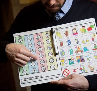 Chaplain Joel Berning holding his spiritual communication board