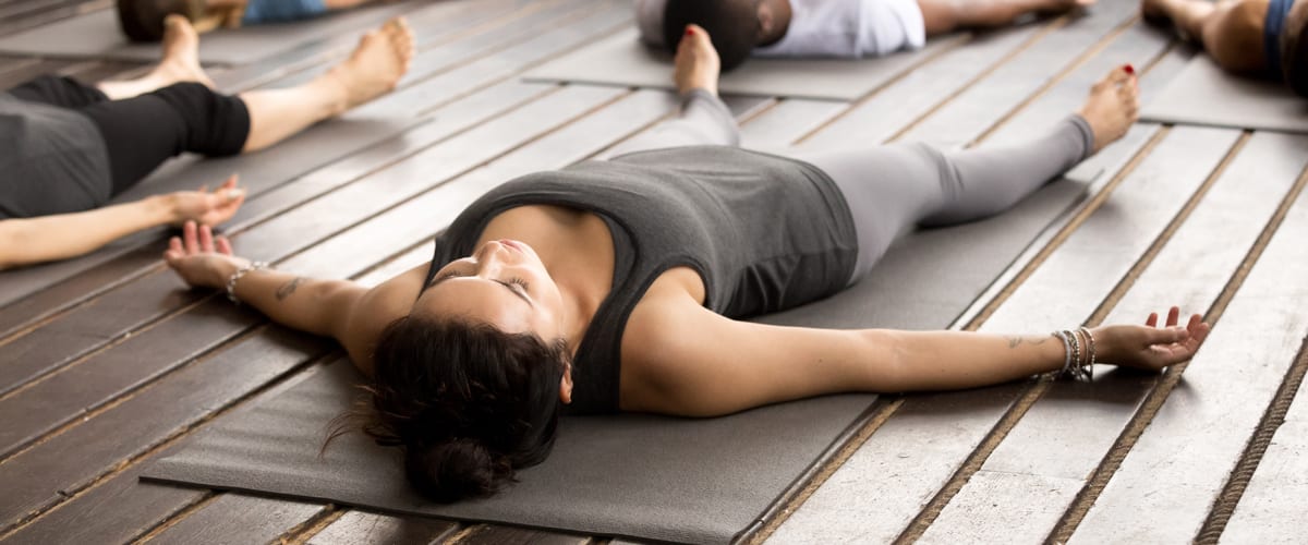 A woman lying on a mat in a yoga class