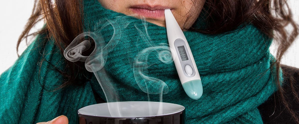 A woman in a scarf taking her temperature