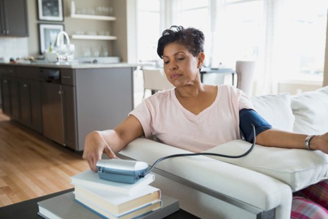 A woman checking her blood pressure at home