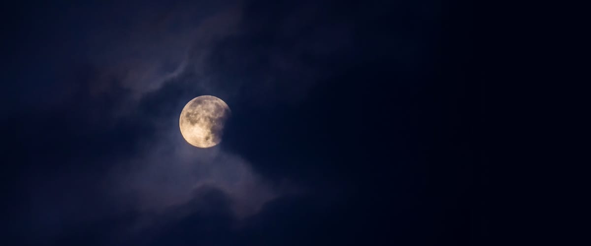 A moon partially hidden by clouds