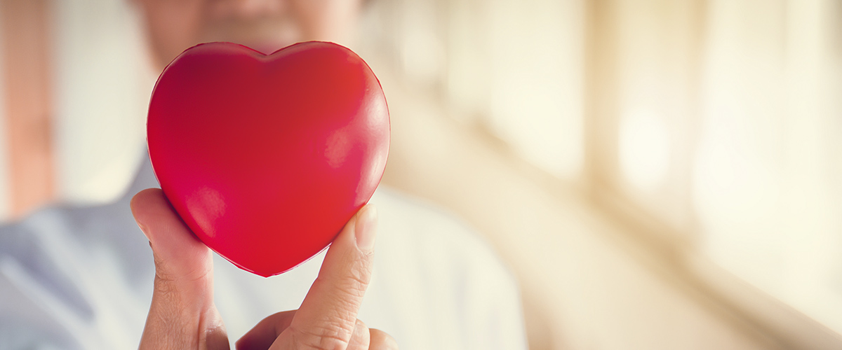 Two fingers holding a rubber toy heart
