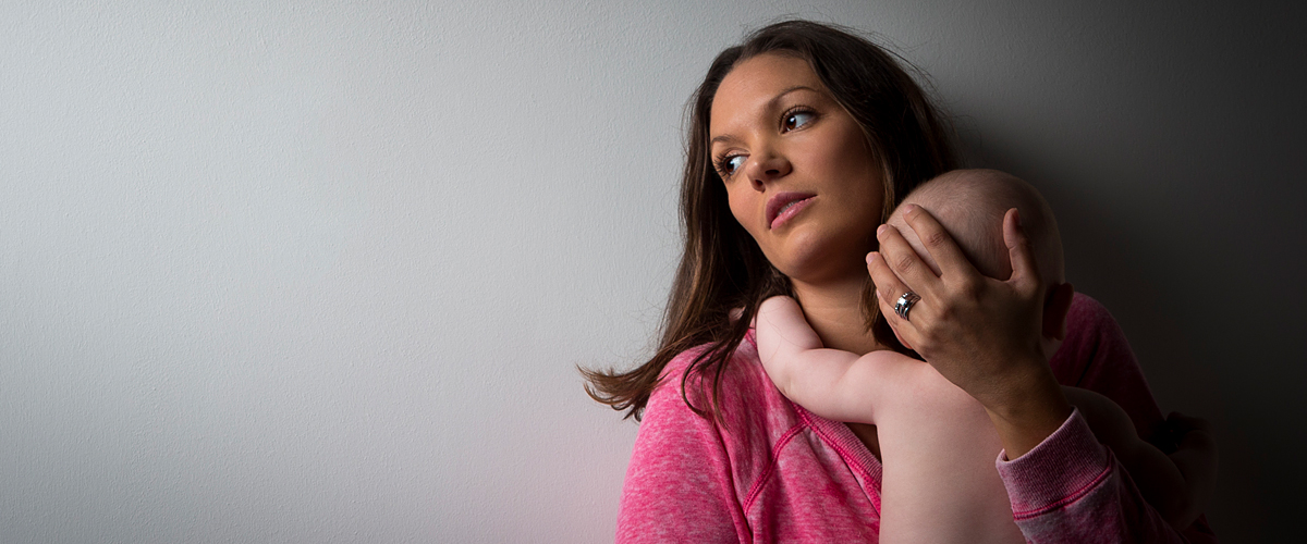 Distressed mother with signs of postpartum depression holding infant