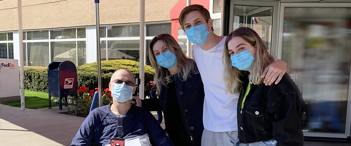After being treated for COVID-19, a recently discharged patient poses with his family.