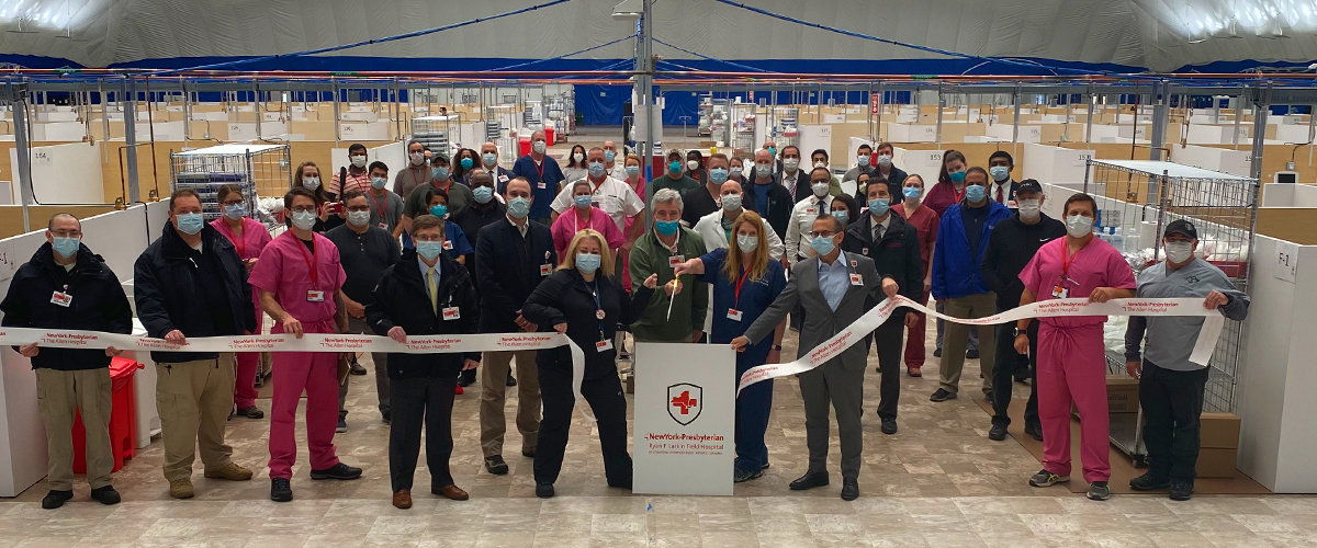 Individuals stand in front of a sign reading Ryan Larkin Field Hospital