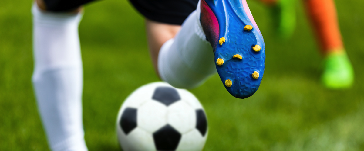 Cleated shoe kicking a soccer ball