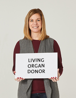 Living organ donor Tracy Kent holding a sign that says "living organ donor."