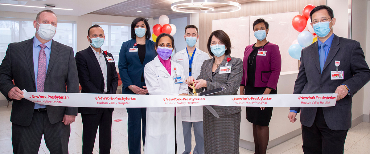 Men and women stand in front of a banner with a large pair of scissors