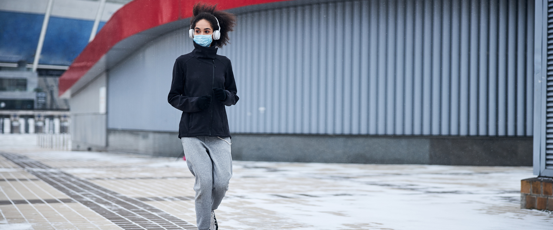 Woman running outdoors, wearing a mask.